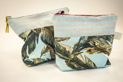 zwei Kulturbeutel mit einem Stoff auf dem Palmen sind